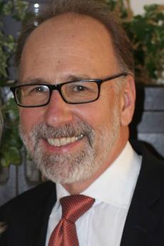 Headshot of man in suit jacket and glasses.